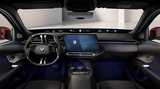 Moderner Innenraum der neuen BMW 3er Limousine mit BMW Lenkrad, großem zentralem Touchdisplay, digitaler Instrumentenanzeige und blauer Ambientebeleuchtung.