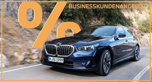 Das Bild zeigt eine dunkelblaue BMW 5er Limousine auf einer kurvigen Straße. Oben steht der Text „GEWERBEKUNDENANGEBOT“ und links ein großes, oranges Prozentsymbol. Ein orangefarbener Rahmen umgibt das gesamte Bild.