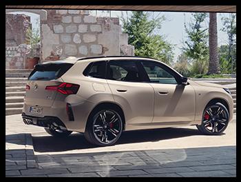 Die Rückansicht des BMW X3 M50 zeigt ein markantes Heck mit vier Endrohren, einem sportlichen Diffusor und den neu gestalteten LED-Rückleuchten in einer hellen Sand-/Beige-Lackierung.