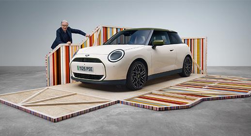 Designer Sir Paul Smith präsentiert die exklusive MINI Paul Smith Edition: Ein cremeweißer MINI Cooper mit grünem Dach auf einer Installation mit den ikonischen bunten Streifen des Designers.