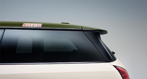 Seitenansicht der Heck- und Dachpartie der MINI Paul Smith Edition: Olivgrünes Fahrzeugdach mit einer kleinen Plakette im bunten Paul Smith Streifendesign über den getönten Seitenscheiben.