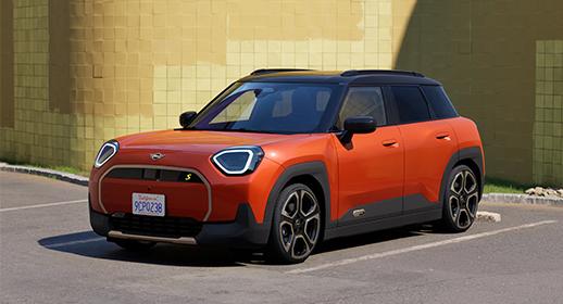 Oranger Mini Aceman SUV geparkt vor einer gelben Ziegelwand.