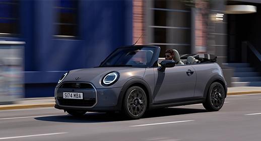 Graues Mini Cooper Cabrio fährt auf einer Stadtstraße.