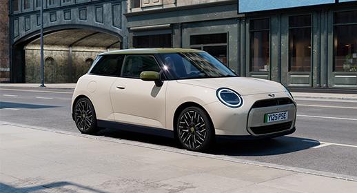 Der vollelektrische MINI Cooper E der limitierten Paul Smith Edition in Cremeweiß mit olivgrünem Dach, geparkt an einer städtischen Straße vor historischer Kulisse