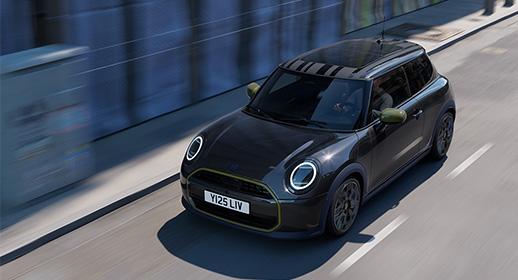 Ein dunkelblauer MINI Cooper der limitierten Paul Smith Edition in voller Fahrt auf einer Straße, erkennbar an den olivgrünen Außenspiegeln und dem gestreiften Dachdesign.