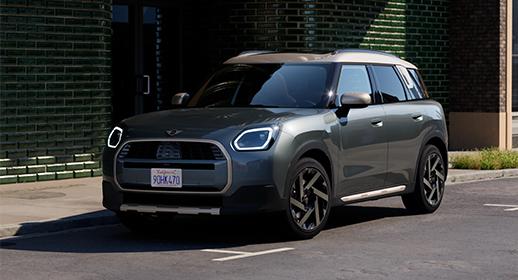 Dunkelgrauer Mini Countryman SUV geparkt vor einer Ziegelwand.
