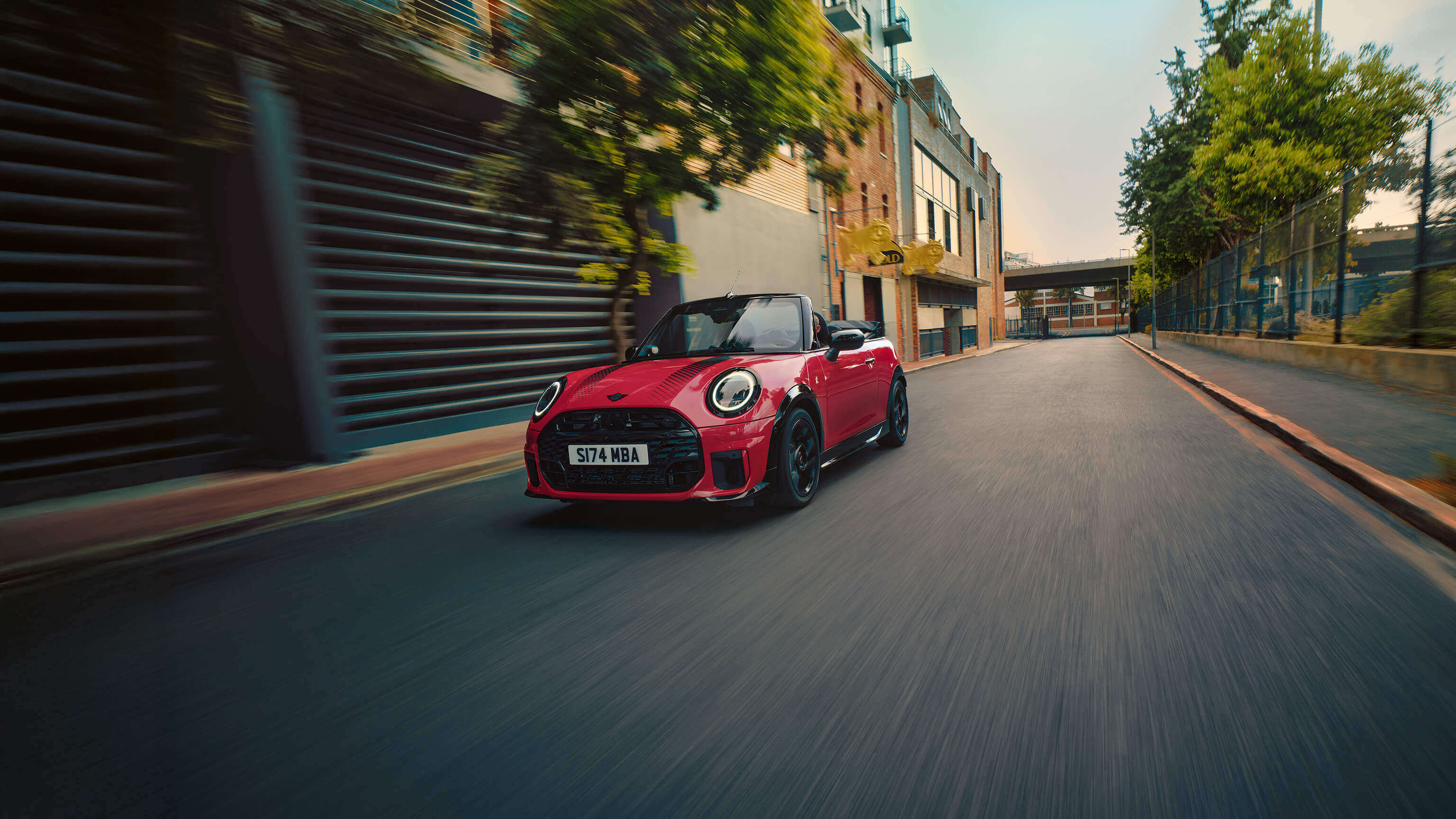  Sie haben ein Bild eines roten MINI Cooper Cabrios hochgeladen, das dynamisch auf einer urbanen Straße fährt.