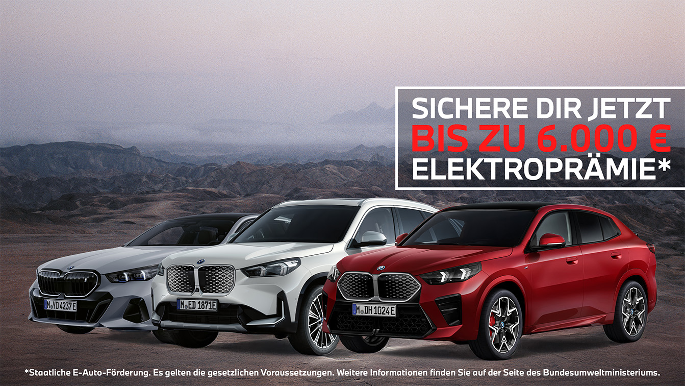 Das Bild zeigt eine Werbegrafik für elektrische BMW-Modelle vor einer weiten, nebligen Gebirgskulisse in erdigen Brauntönen. Im Vordergrund präsentieren sich drei moderne Fahrzeuge – ein silbergraues Auto, ein weißer SUV und ein markanter roter SUV-Coupé – die alle schräg in Richtung des Betrachters positioniert sind. Am rechten oberen Bildrand sticht ein weiß umrandetes Textfeld hervor, das mit der Aufschrift „SICHERE DIR JETZT BIS ZU 6.000 € ELEKTROPRÄMIE*“ wirbt, wobei der Geldbetrag in leuchtendem Rot besonders hervorgehoben ist. Ein kleiner weißer Disclaimer am unteren Rand verweist darauf, dass es sich um eine staatliche Förderung handelt und weitere Informationen beim Bundesumweltministerium zu finden sind.
