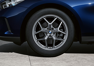Nahaufnahme eines BMW Winterkomplettrads mit Y-Speichen-Felge in Lightning Grey an einem blauen BMW.